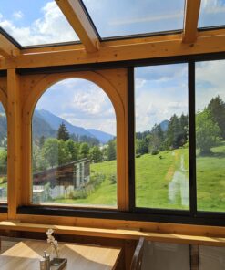 Wintergarten des Hotels Berghof in Nesselwängle mit Blick auf grüne Wiesen und Berge