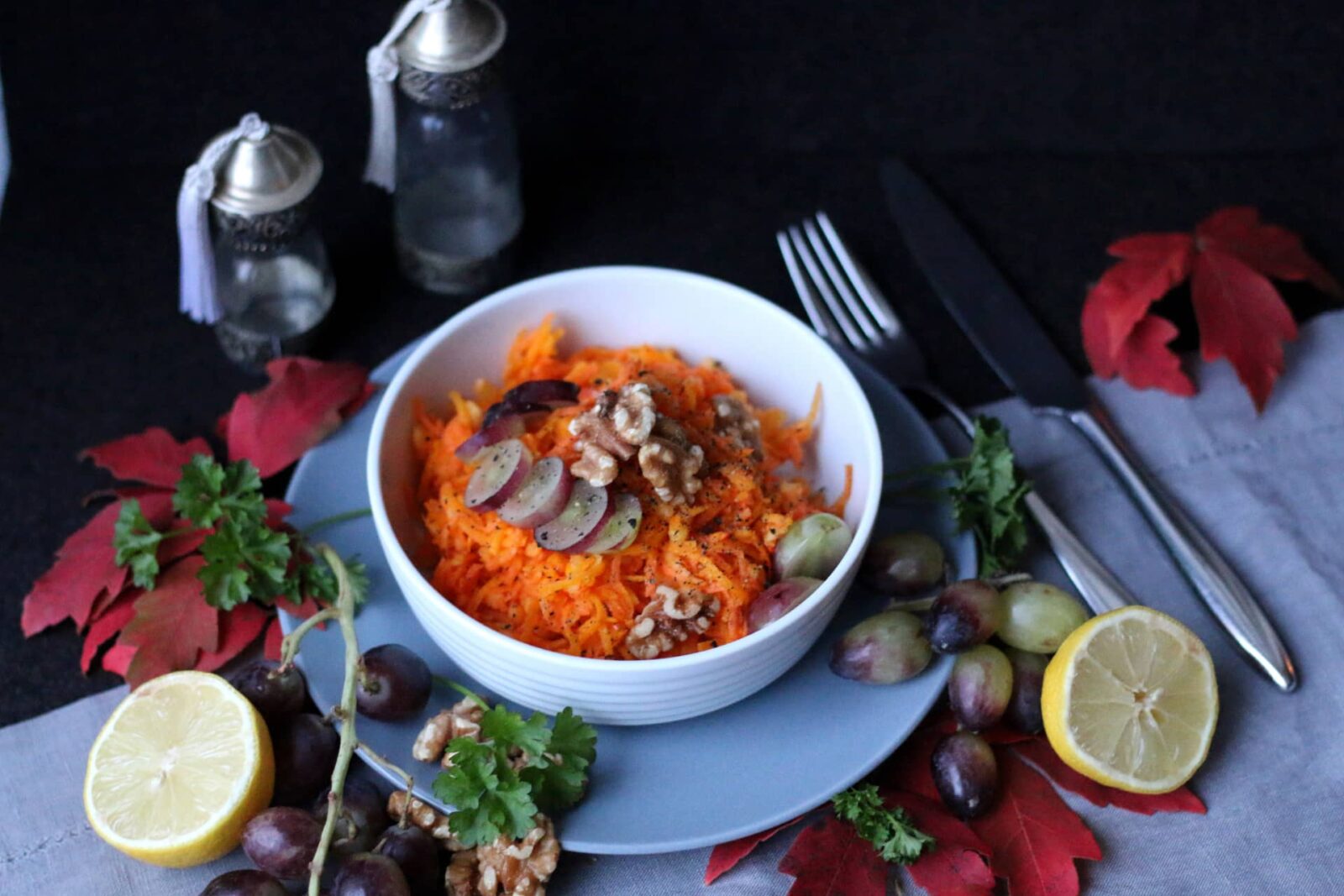Karottensalat in einer Schale, angerichtet mit Walnüssen und Trauben