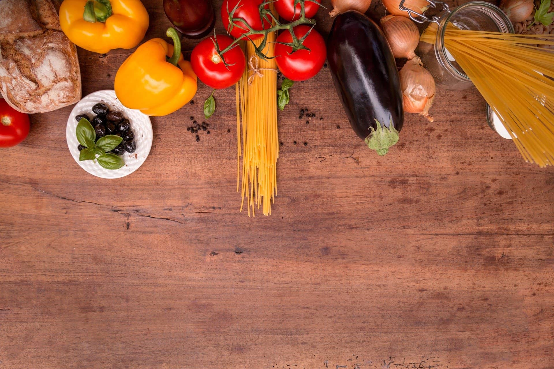 Mediterranes Gemüse und Nudeln am oberen Rand eines dunklen Holztisches