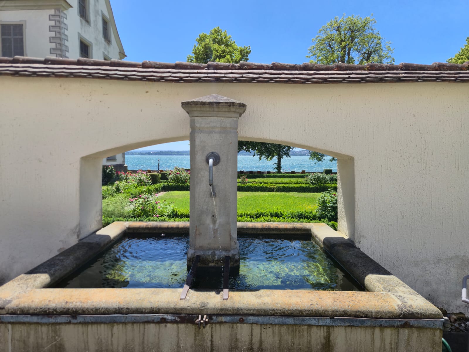 Brunnen im Garten von Schloss Maurach mit dem Bodensee im Hintergrund