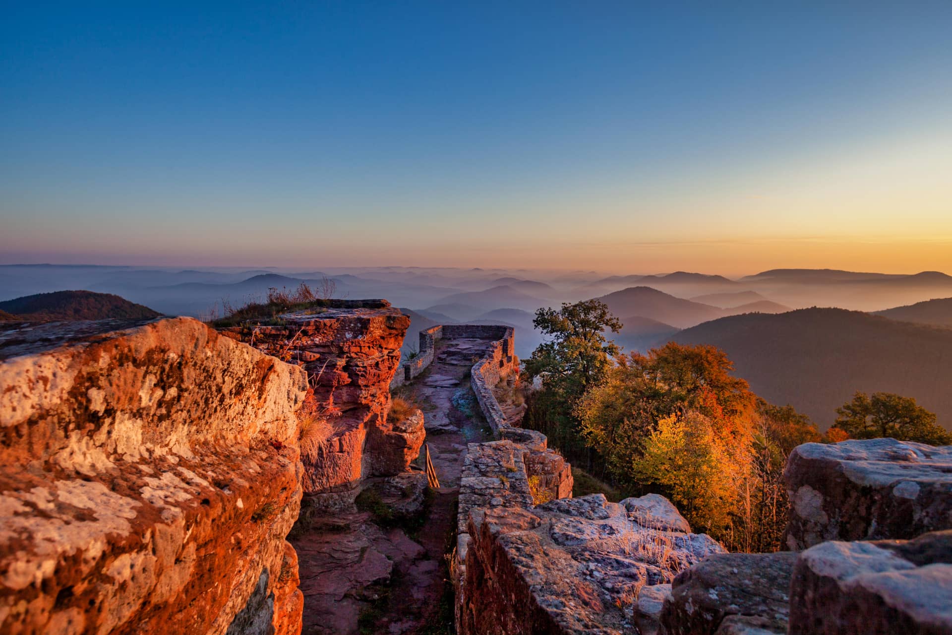 Wegelnburg im Pfälzerwald im Sonnenaufgang mit Nebel im Tal