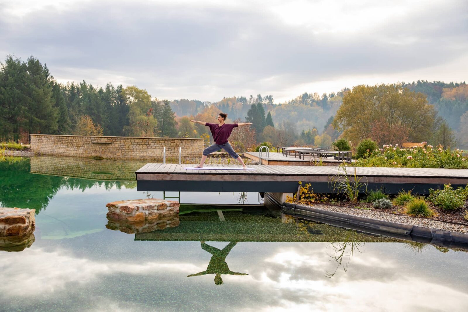 Frau beim Yoga auf einem Steg im Badeteich des Pfalzblick Wald Spa Resorts in Dahn